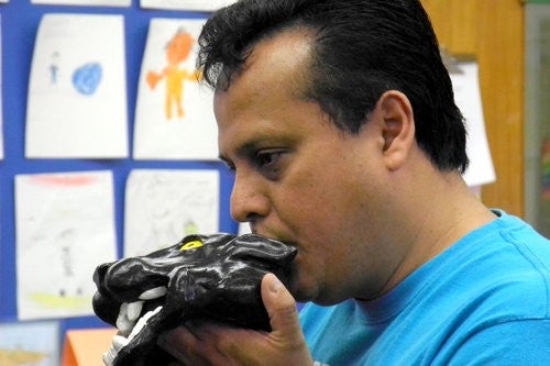 Samuel Becerra playing an Aztec instrument shaped like a jaguar head