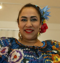 Kenya Marquez a smiles, wearing flowers in her hair.