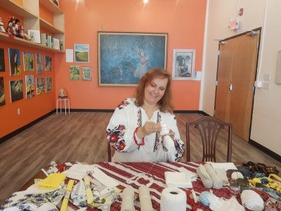 Shatalova sits at a table and starts a Motanka doll.